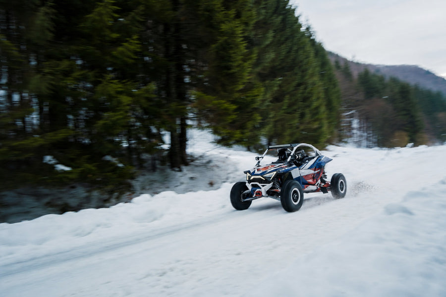 UTV with red white and blue high-tack graphics driving through winter off-road conditions