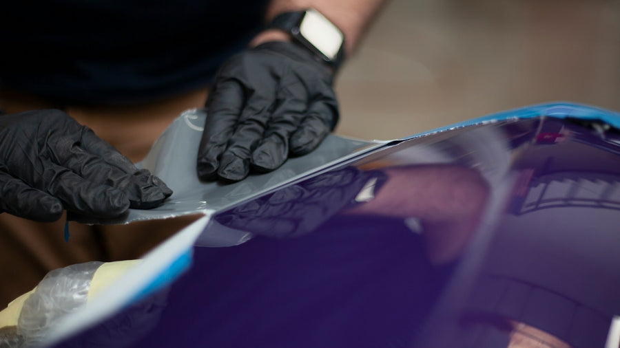 Installer applying flexible film over a curved vehicle body panel